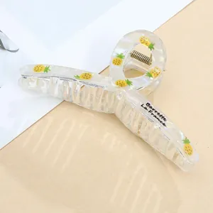 Detail of transparent acrylic hair claw with pineapple print and golden metal spring