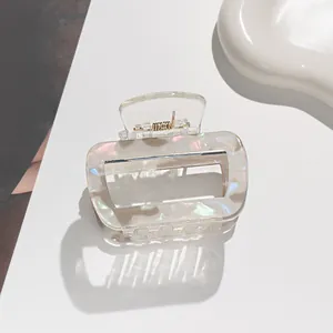 Macro shot of rectangular pearlescent hair claw clip with golden metal spring detail
