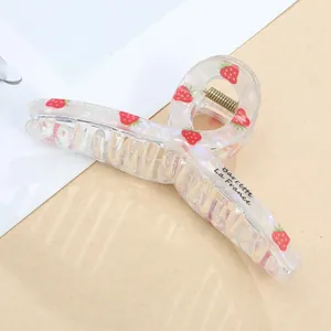 Detail of transparent hair claw clip with red strawberry patterns and decorative lettering
