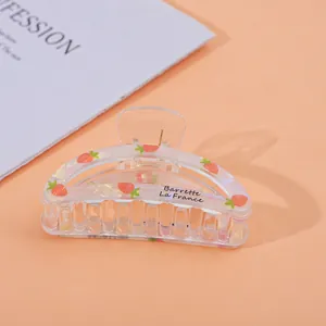 Detailed close-up of transparent acrylic hair claw clip with pink strawberry pattern