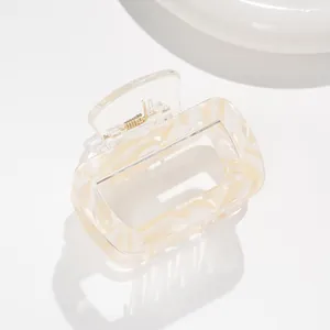 Macro shot of square hair claw clip featuring yellow cream marble pattern and metal spring