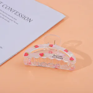 Detail of translucent strawberry hair claw clip with colorful finish on pink background