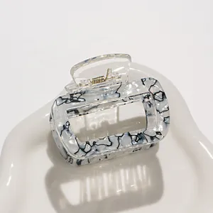 Detail of square hair claw clip featuring elegant black and white marble resin texture