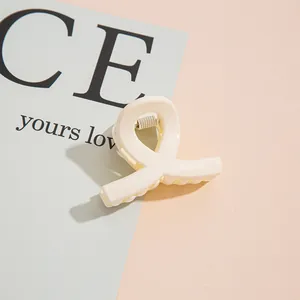 Détail d'une pince à cheveux minimaliste blanc crème avec un design lisse en cœur