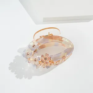 Detail of floral hair claw clip with marble texture acrylic and sparkling rhinestones