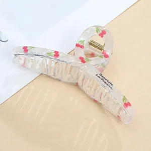 Detailed view of transparent acrylic hair claw with cherry print and golden spring