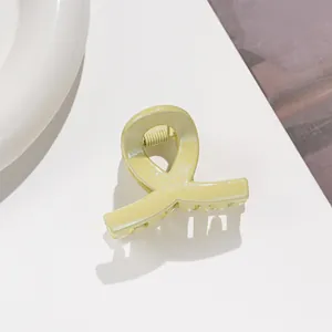 Détail de la pince à cheveux jaune pâle à paillettes avec design croisé et ressort