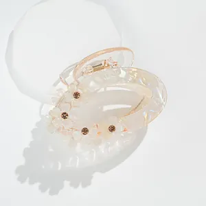 Macro view of translucent resin hair claw clip with floral motifs and rhinestone detail