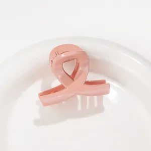 Gros plan sur une mini pince à cheveux rose pailletée avec design à nœud croisé
