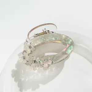 Macro shot of iridescent acrylic flower hair claw with small rhinestone details