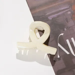 Détail macro d'une pince à cheveux crème pailletée avec design croisé évidé