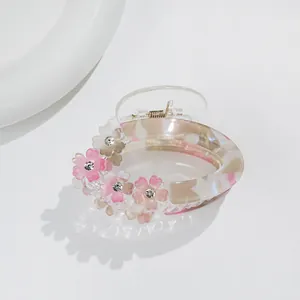 Close-up of marble pattern hair claw clip with floral accents and sparkling rhinestones
