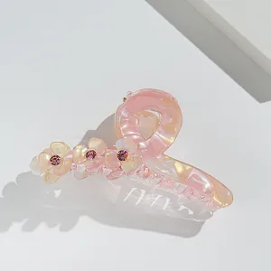 Detail of pink acrylic flower hair claw clip with rhinestones and pearl finish