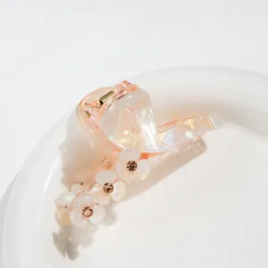 Detail of pink pearlescent flower hair claw clip with rhinestones on a ceramic dish