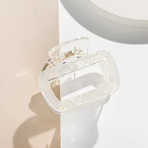 Detail of aurora rectangle hair claw clip with golden metal spring on beige background