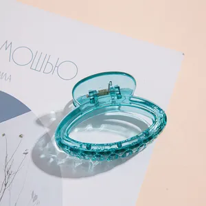 Dettaglio di una mini molletta per capelli ciano trasparente con design ovale cavo