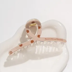 Detail of polka dot acrylic claw clip with gold spring on a ceramic tray