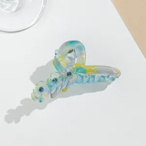 Detail view of large clover acrylic hair claw with iridescent blue and yellow floral design