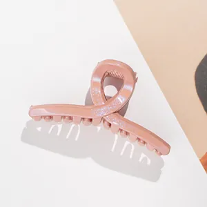 Detail of peach pink glitter hair claw clip with crossed design and shimmer finish