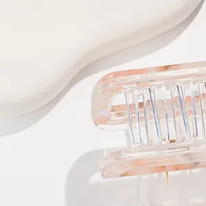 Dettaglio ravvicinato di una molletta per capelli in acetato rosa con trama marmorizzata
