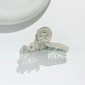 Detail of clover hair claw clip with iridescent finish and rhinestone-studded floral accents