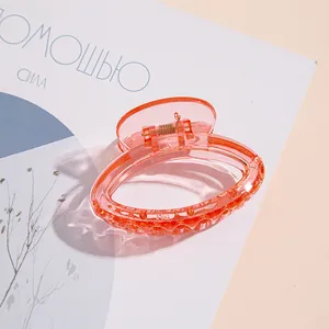 Vista dettagliata di una clip per capelli trasparente rosa corallo con molla in metallo