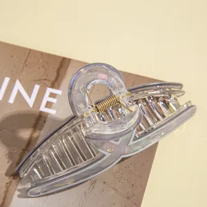 Makroaufnahme einer schillernden Acryl-Haarklammer mit goldener Metallfeder auf Magazin