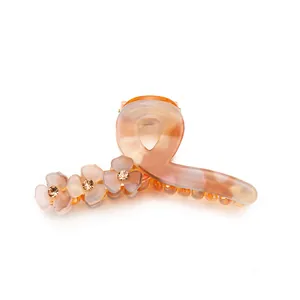 Translucent amber acrylic hair claw clip with frosted purple flowers and sparkling rhinestones