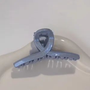 Detail of Morandi blue hair claw clip with a glitter finish and twisted cross design