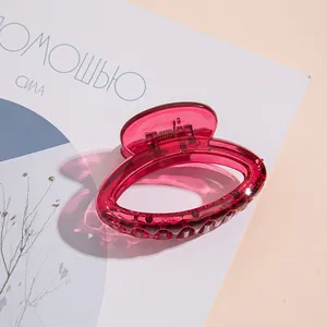 Dettaglio di una mini clip per capelli rosso rosa traslucido con finitura lucida e molla