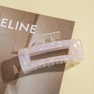 Close-up of a square iridescent purple hair claw clip with pearl texture on a magazine