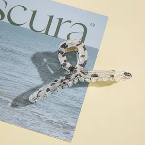Pinza per capelli in acrilico con stampa leopardata e molla dorata su sfondo semplice