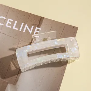 Macro detail of iridescent pearl white rectangle hair claw clip with marble texture