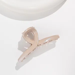 Macro detail of glossy khaki hair claw clip with subtle glitter finish and cross design