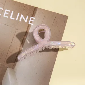 Detail einer hellrosa marmorierten Haarklammer mit goldener Feder auf einem Magazin