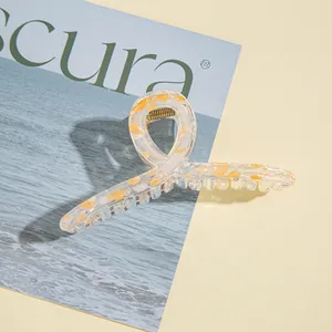 Dettaglio ravvicinato della grande pinza per capelli in acrilico con trama tartarugata arancio