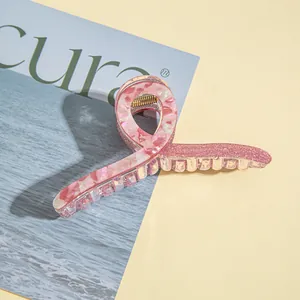 Detail of pink acrylic claw clip with marble texture and glitter finish design