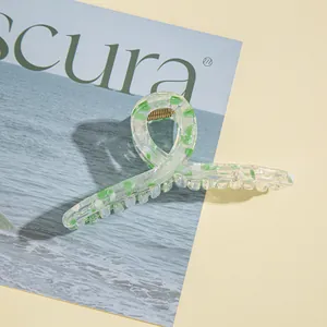 Dettaglio della molletta per capelli in resina terrazzo verde e bianca con molla dorata