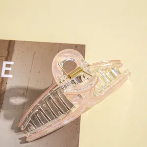 Close-up of translucent pink large hair claw clip with golden metal spring detail
