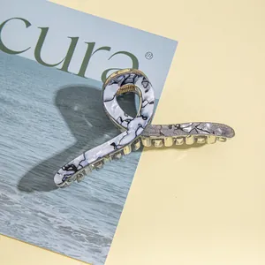 Detail of a large gold metal hair claw with blue marble resin finish on a magazine