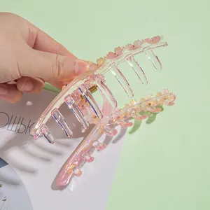 Détail d'une pince à cheveux en résine rose avec fleurs 3D et ressort en métal robuste