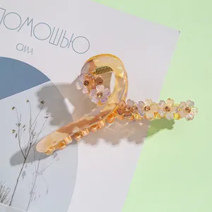 Détail macro de la pince à cheveux en résine ambre avec fleurs nacrées et strass brillants