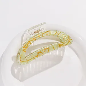 Close-up of pale green resin hair claw with golden marble pattern and transparent handle