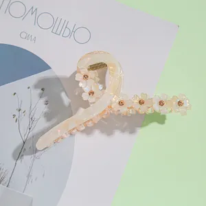 Détail d'une pince à cheveux en acétate crème avec motifs floraux et strass ambrés