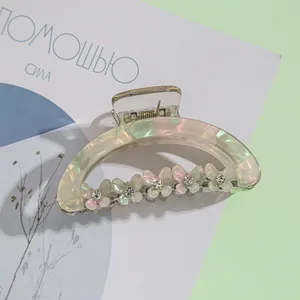 Détail d'une pince à cheveux papillon vert irisé ornée de strass brillants et élégants