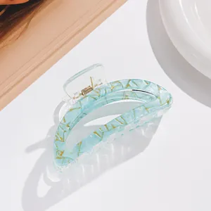 Detail of mint green hair claw clip with golden marble texture and strong metal spring