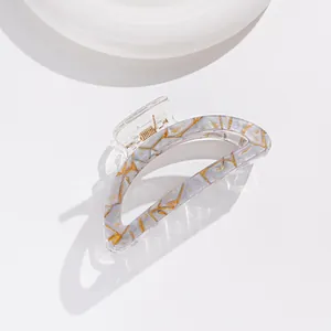 Detail of gray marble acetate hair claw clip with gold foil accents and metal spring