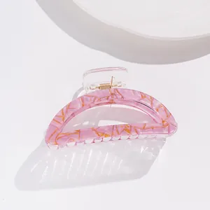 Detail of pink marble pattern hair claw clip with gold accents and strong metal spring