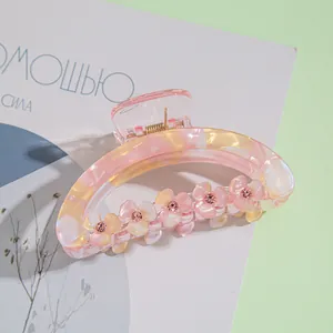 Detail of pink floral hair claw clip with rhinestones on a decorative background