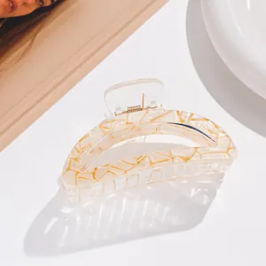 Macro detail of medium claw clip with white and gold marble texture in a stylish setting